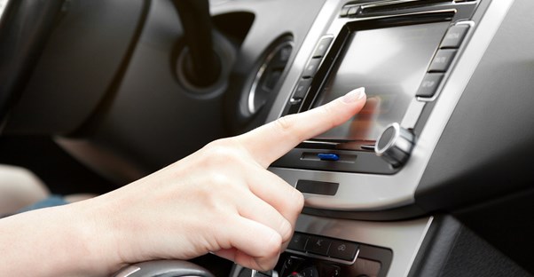 a person interacts with the GPS unit in the car dashboard