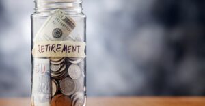 A jar labeled RETIREMENT holding spare change to represent a reason you need a financial adviser.