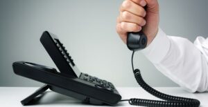 A business owner clutches a phone in frustration because of the disadvantages of his business phone service.