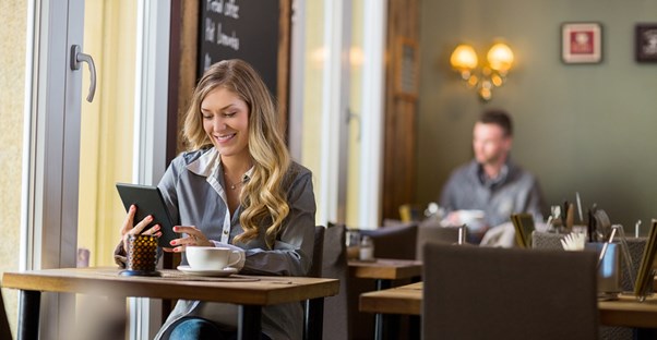 a woman enjoys discreetly reading 50 shades of gray on her tablet in a coffee shop