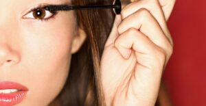 a woman applies mascara to her eyelashes