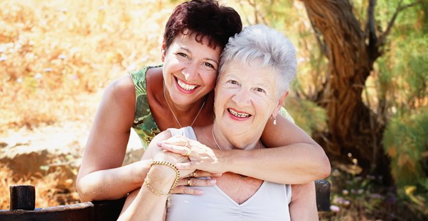 A woman and her ailing mother hug after discussing elder care.
