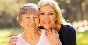 Woman and her ill mother smile, enjoying the time they spend together with at home care