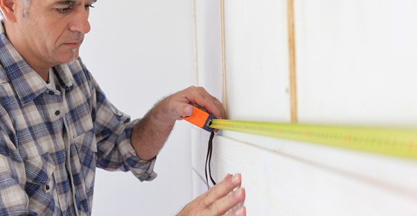 a man measures his bathroom for a remodel