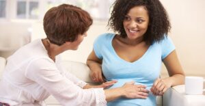 Midwife shares a tender moment with her lesbian partner as she feels the unborn baby kick