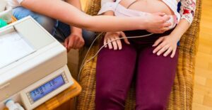 Midwife feels up the belly of a pregnant woman
