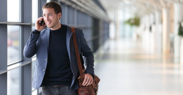 a businessman talks on his phone before boarding a plane