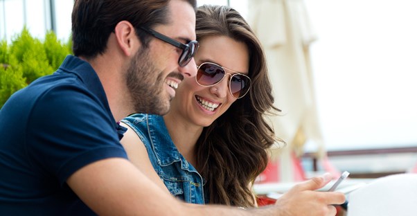 two travelers review their travel app while at a cafe