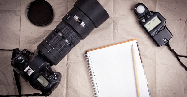 camera lenses and other gaer lie on a bed ready to be packed