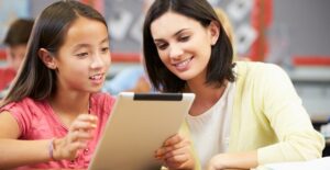A substitute teacher shows a student something interesting on a tablet