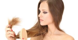 Young woman examining her split ends and wondering if there's a natural hair treatment for them