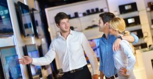 A salesman discuss flatscreen tv sizes with cusomters