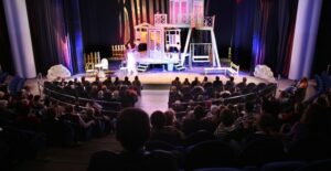 the curtain opens on a broadway set
