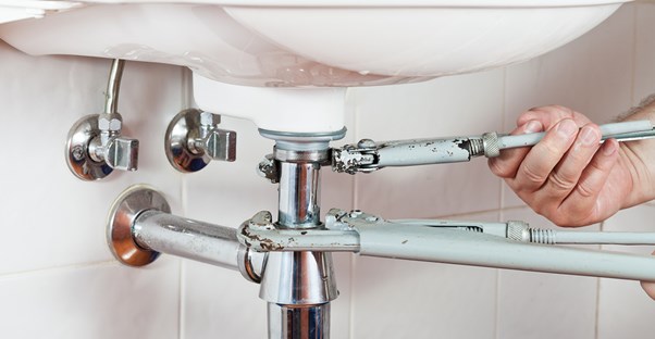 Hand touching a pipe on a sink