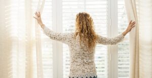 Woman opening her economical window treatments