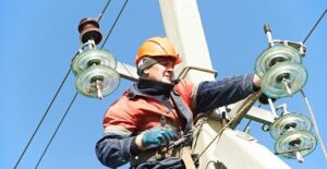 Electrician fixes broken wires on pole