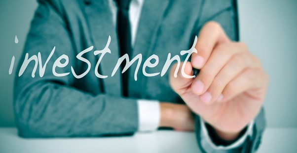 Man in suit writing investment on a board