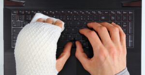 Someone with a broken hand types on a keyboard