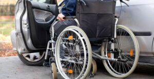A man in a wheelchair gets into a vehicle
