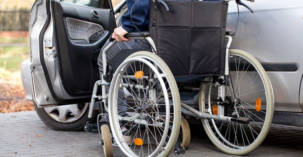 A man in a wheelchair gets into a vehicle