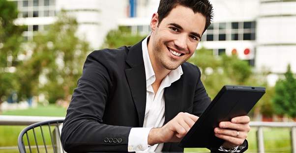 Young man smiles as he plays on his tablet