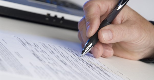Man hand signing his title insurnace policy with a pen