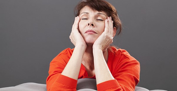 A woman holds her face in her hands to deal with the pain.