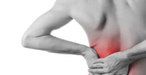 a man holds his back where he is experiencing muscle pain