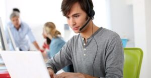 Man types on his laptop and speaks into his bluetooth headset