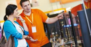 A salesman explains an appliance warranty to a shopper
