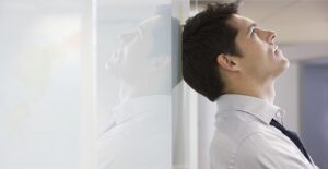 Man leans his head against a wall in frustration
