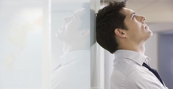 Man leans his head against a wall in frustration