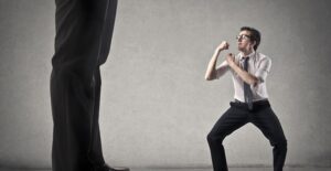 A miniature person puts up his dukes to fight a pair of giant legs