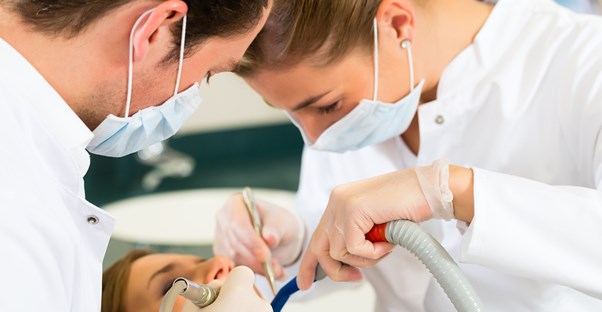 A dentist and a dental hygienist look inside a mouth