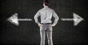 Man stands in front of a chalkboard that has two arrows pointing opposite directions