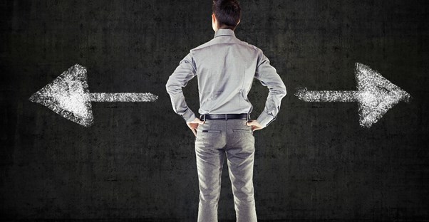 Man stands in front of a chalkboard that has two arrows pointing opposite directions