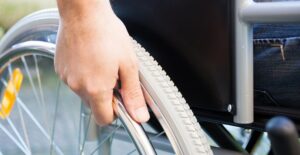 Hand holding the wheel of a wheelchair