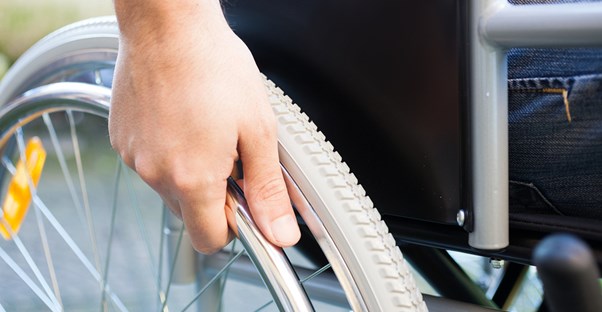 Hand holding the wheel of a wheelchair