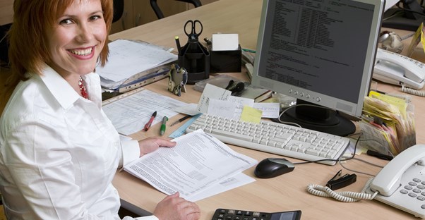 A computer programmer takes a break from her paperwork to smile at the camera