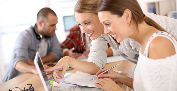 Students look and point at something on a laptop