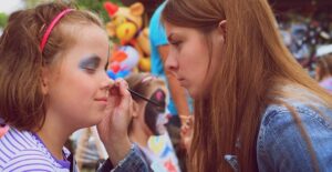 A woman doing her sister's halloween makeup