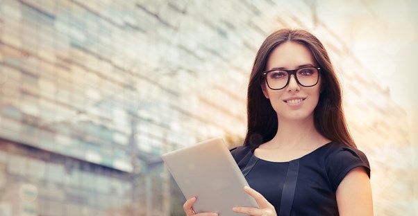 Girl with brown hair and glasses holds up a tablet