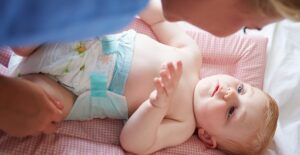 a mother uses diaper rash cream on her baby