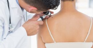 A dermatologist checks a mole on a patient