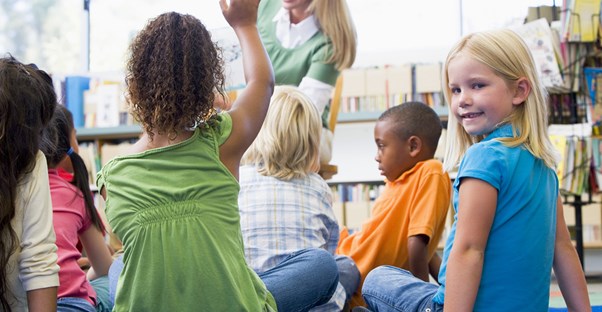 Students raise their hands to answer a question asked by their teacher