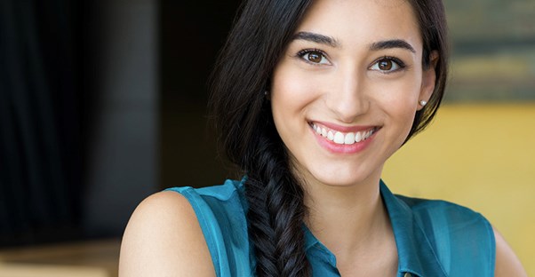 A young girl with a long dark braid smiles at the camera.