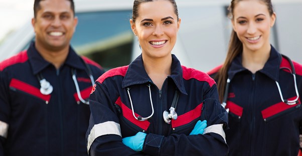A team of EMTs stand and smile after a job well done