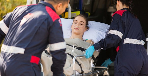 EMTs lift a girl on a stretcher into the ambulance