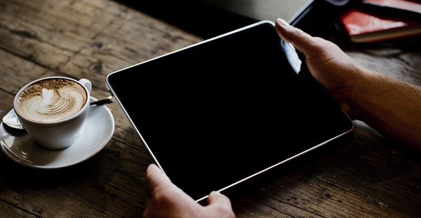 A man enjoys his newly purchased tablet over a cup of coffee.