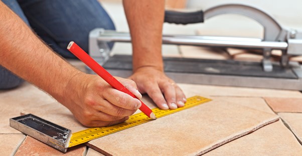 Man measuring out tile for his bathroom